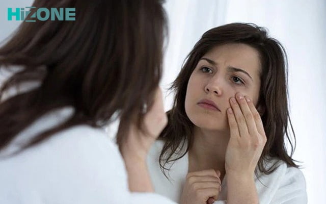 یک زن جلوی آیینه درحال بررسی مضرات پرایمر سیلیکونی روی صورت